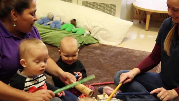 Daycare teachers teaching little babies music with drum and sticks.