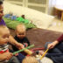 Daycare teachers teaching little babies music with drum and sticks.