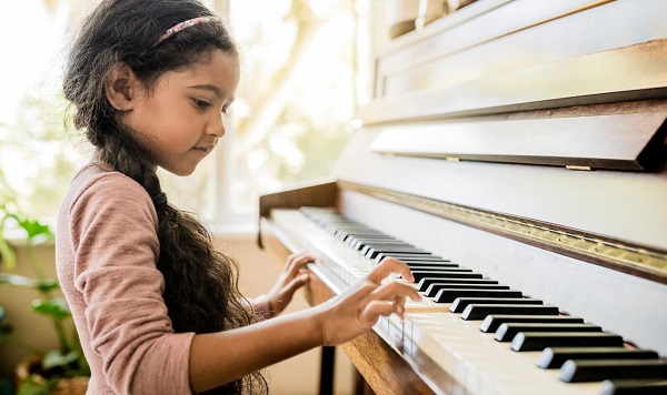 A little girl learning playing piano with her tiny hands
