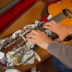 A man (face not seen) packing his guitar in a box.